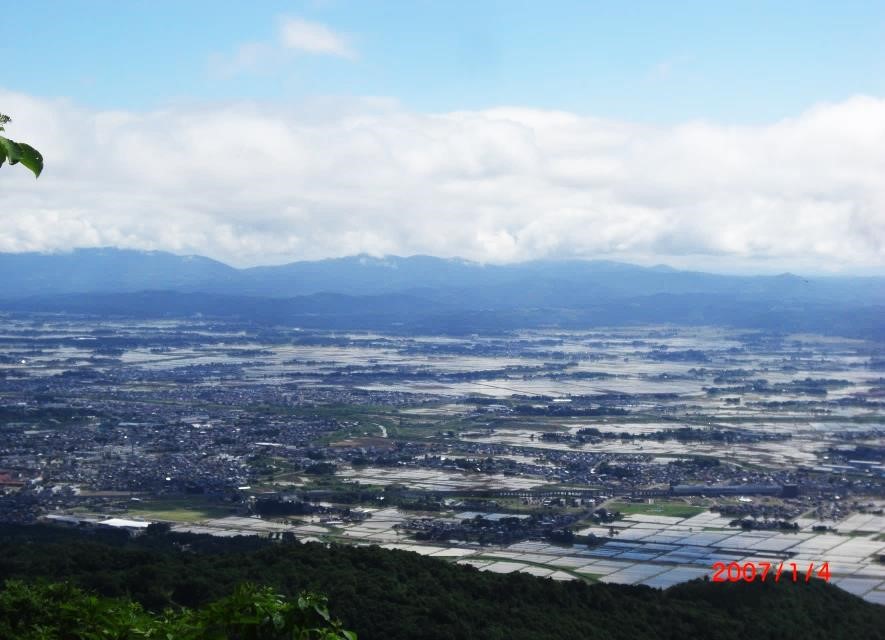 高田平野の田園地帯の先に東頸城丘陵